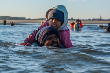 அபாயகரமான முறையில் குழந்தைகளுடன் கடலுக்குள் இறங்கும் புலம்பெயர்வோர்: பதறவைக்கும் காட்சிகள்