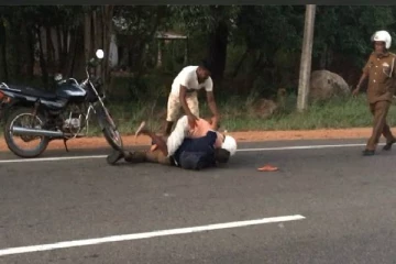 வீதியில் பொலிஸ் அதிகாரியை புரட்டி போட்டு தாக்கிய இருவர்